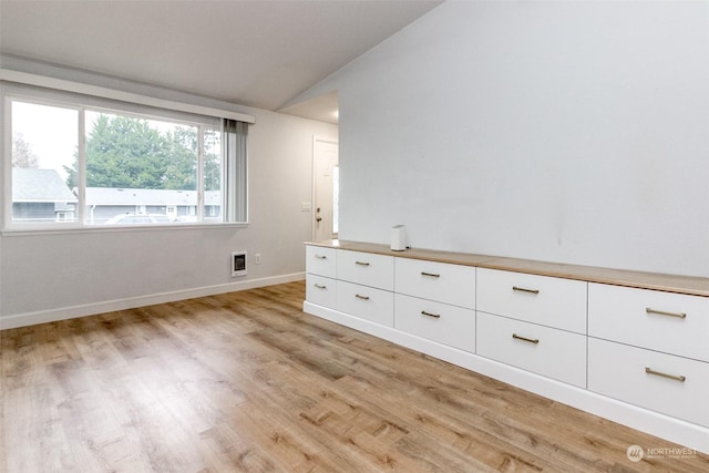 unfurnished room featuring heating unit, vaulted ceiling, and light hardwood / wood-style floors