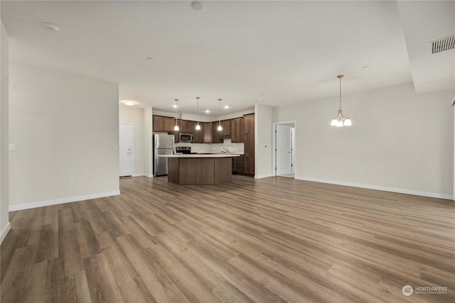 unfurnished living room featuring hardwood / wood-style floors and an inviting chandelier