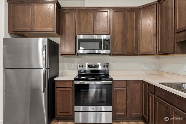 kitchen featuring dark brown cabinets, stainless steel appliances, and sink