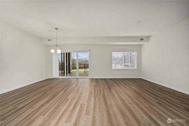 unfurnished room featuring plenty of natural light, light hardwood / wood-style flooring, and an inviting chandelier