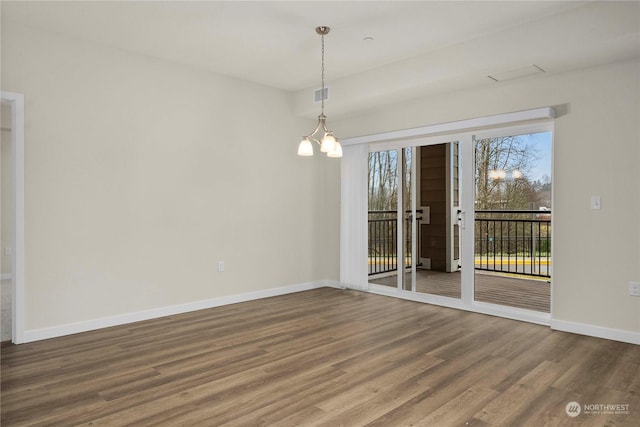 spare room featuring hardwood / wood-style floors and an inviting chandelier