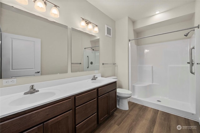 bathroom featuring walk in shower, hardwood / wood-style floors, vanity, and toilet