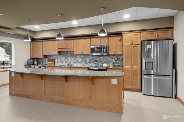 kitchen with pendant lighting, a kitchen breakfast bar, sink, appliances with stainless steel finishes, and light stone counters