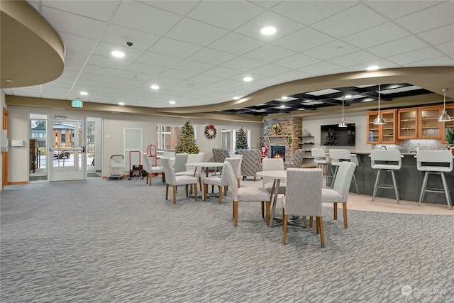 dining area with carpet, a stone fireplace, and a wealth of natural light