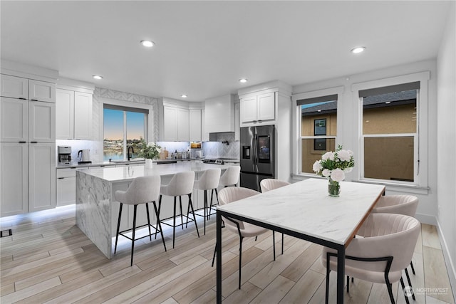 kitchen with sink, stainless steel fridge, tasteful backsplash, a kitchen island, and white cabinetry