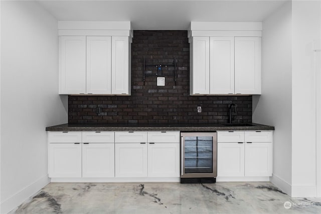 kitchen with dark stone counters, sink, tasteful backsplash, white cabinetry, and beverage cooler