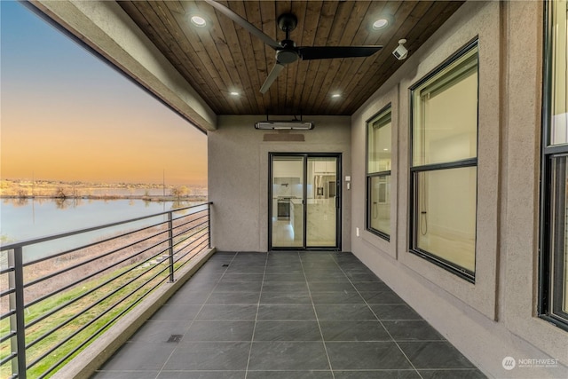 balcony at dusk featuring a water view