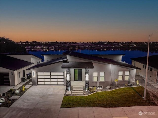 view of front of home featuring a lawn, a garage, and a water view