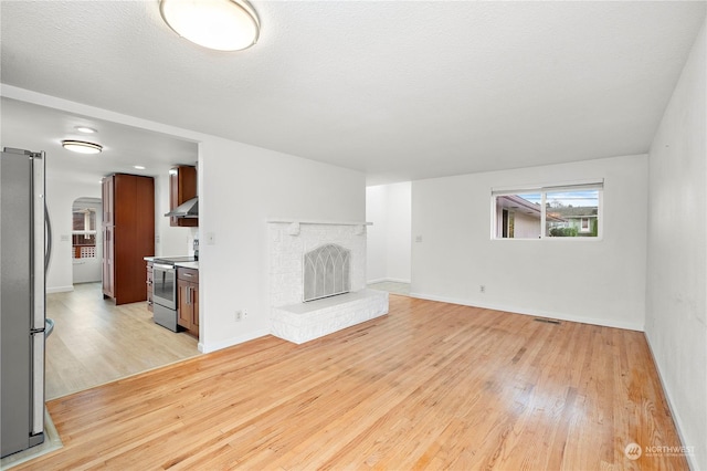 unfurnished living room with a fireplace, light hardwood / wood-style flooring, a barn door, and a textured ceiling