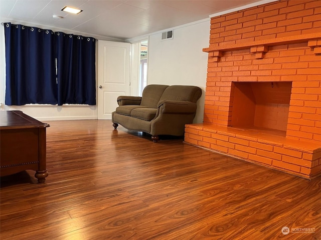 sitting room featuring a brick fireplace, hardwood / wood-style flooring, and ornamental molding