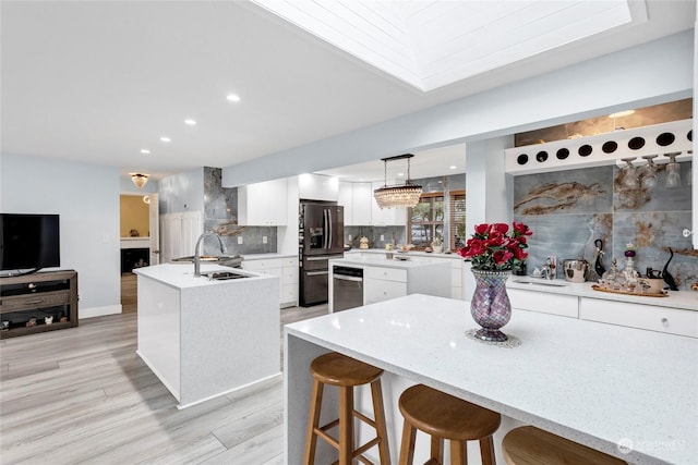 kitchen with backsplash, a kitchen island with sink, white cabinets, stainless steel fridge with ice dispenser, and hanging light fixtures