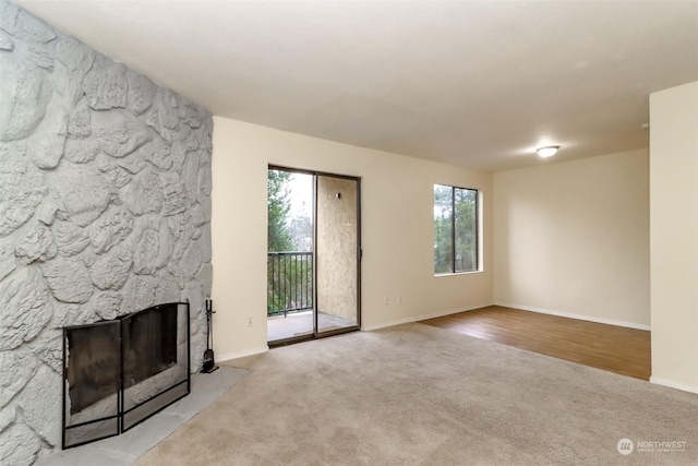 unfurnished living room with a fireplace, light colored carpet, and plenty of natural light