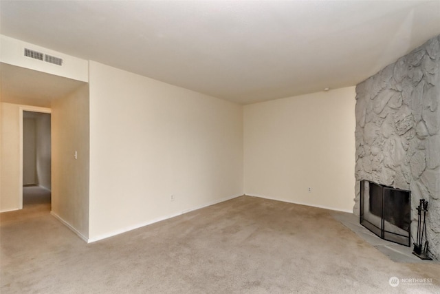 unfurnished living room featuring a stone fireplace and light colored carpet