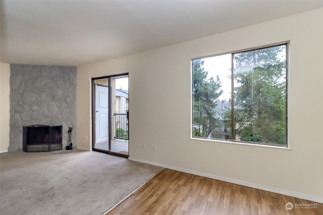 unfurnished living room featuring carpet flooring and a stone fireplace