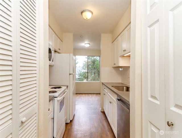 kitchen featuring tasteful backsplash, white appliances, sink, hardwood / wood-style flooring, and white cabinets