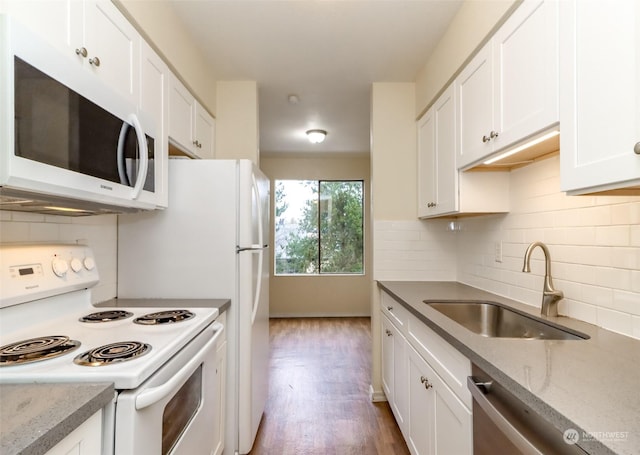 kitchen with light stone countertops, white appliances, white cabinetry, and sink