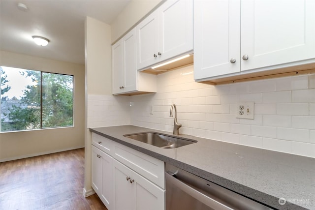 kitchen with sink, stainless steel dishwasher, light stone countertops, tasteful backsplash, and white cabinetry