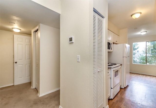 kitchen with white cabinets, light carpet, and white appliances