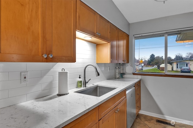 kitchen with sink, light stone counters, stainless steel dishwasher, tile patterned floors, and decorative backsplash