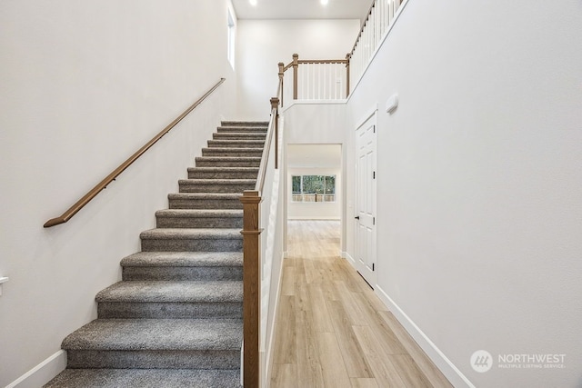 staircase with a towering ceiling and hardwood / wood-style flooring