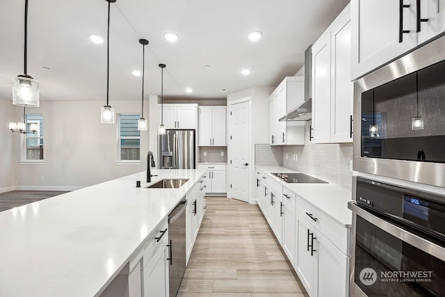 kitchen featuring white cabinetry, appliances with stainless steel finishes, tasteful backsplash, wall chimney range hood, and pendant lighting