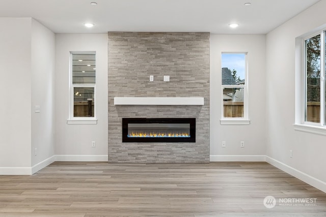 unfurnished living room with a fireplace, a wealth of natural light, and light wood-type flooring