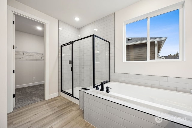 bathroom featuring plus walk in shower and hardwood / wood-style floors