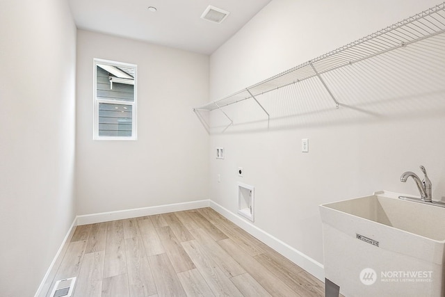 clothes washing area with washer hookup, sink, electric dryer hookup, and light wood-type flooring