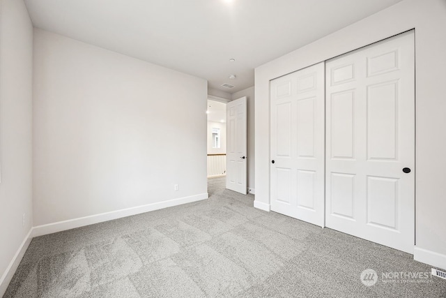 unfurnished bedroom with a closet and light carpet