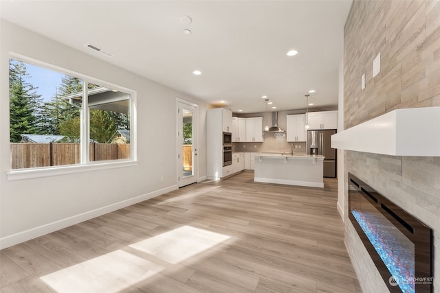 unfurnished living room featuring a tile fireplace and light hardwood / wood-style flooring