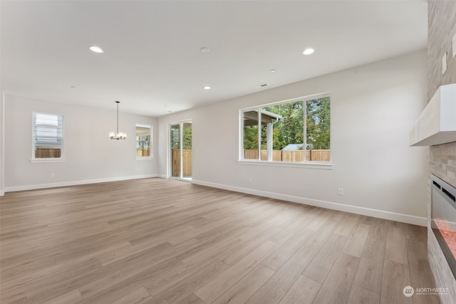 unfurnished living room with a chandelier and light hardwood / wood-style floors