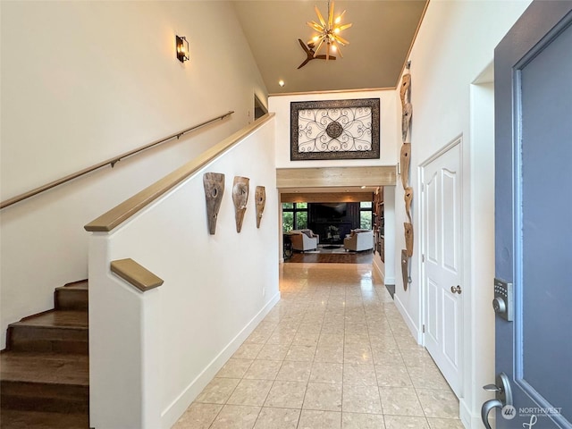 entryway with a notable chandelier, light tile patterned floors, and a high ceiling