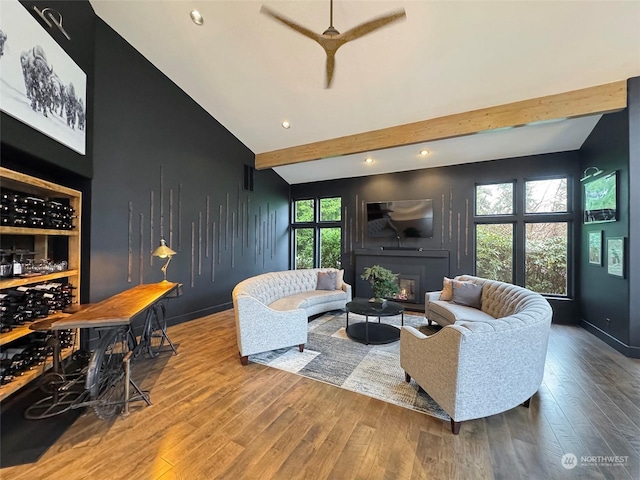 living room featuring lofted ceiling with beams, ceiling fan, and wood-type flooring