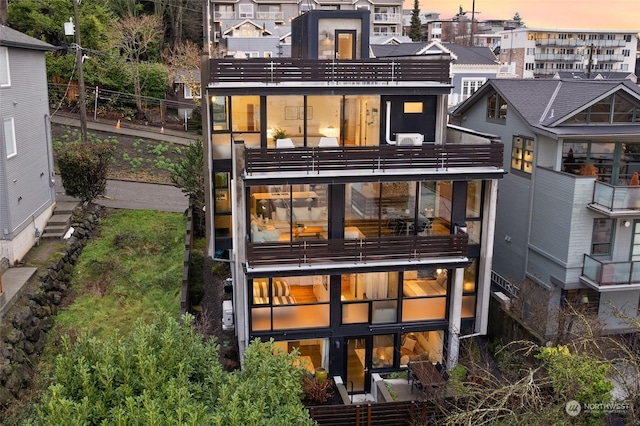 back house at dusk with a balcony