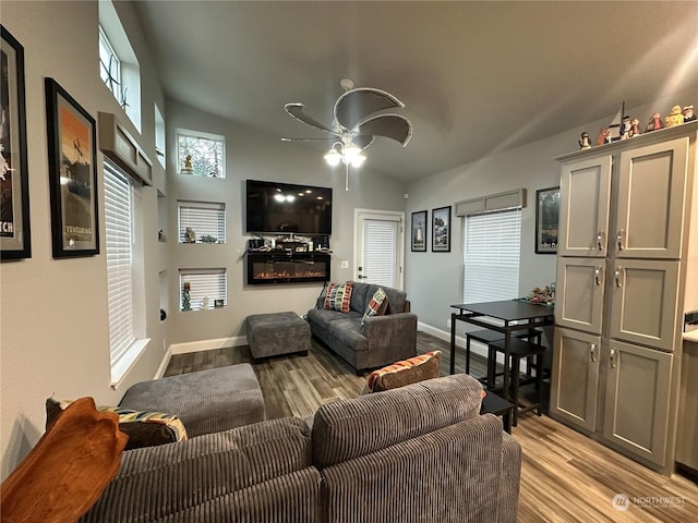 living room featuring ceiling fan, light hardwood / wood-style floors, and vaulted ceiling