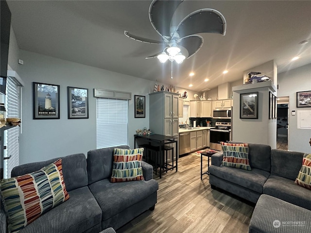 living room featuring ceiling fan, sink, light hardwood / wood-style floors, and vaulted ceiling