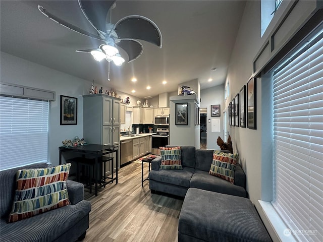 living room featuring vaulted ceiling, light hardwood / wood-style flooring, ceiling fan, and sink