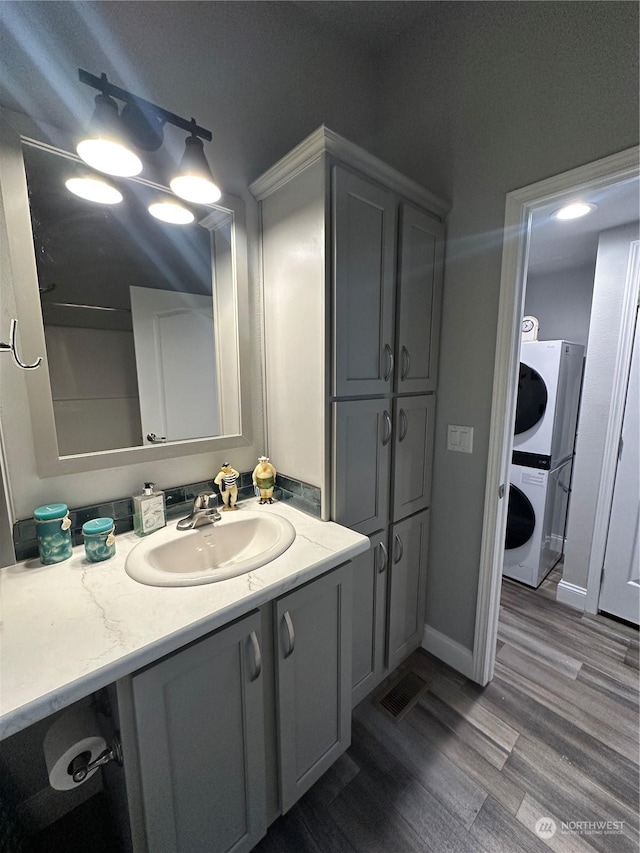 bathroom featuring stacked washer / dryer, hardwood / wood-style floors, and vanity