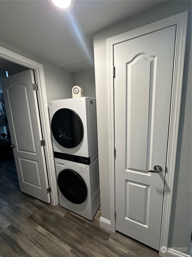 laundry area featuring dark hardwood / wood-style flooring and stacked washing maching and dryer