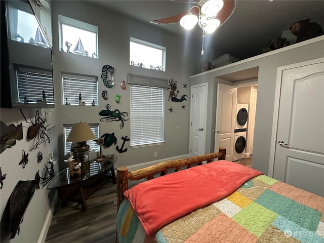 bedroom featuring a high ceiling, dark hardwood / wood-style floors, ceiling fan, and stacked washer / drying machine