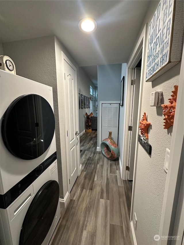 washroom featuring stacked washer / dryer and dark wood-type flooring