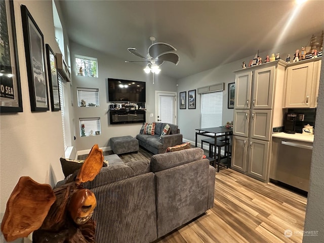 living room with ceiling fan, light wood-type flooring, and vaulted ceiling