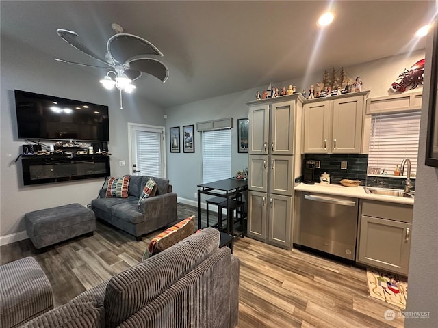 living room with lofted ceiling, ceiling fan, light wood-type flooring, and sink