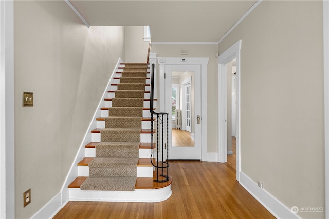 stairs with hardwood / wood-style flooring and ornamental molding