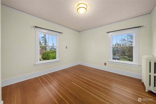 empty room featuring radiator, wood-type flooring, and a wealth of natural light