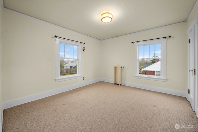 carpeted spare room featuring plenty of natural light, radiator, and crown molding