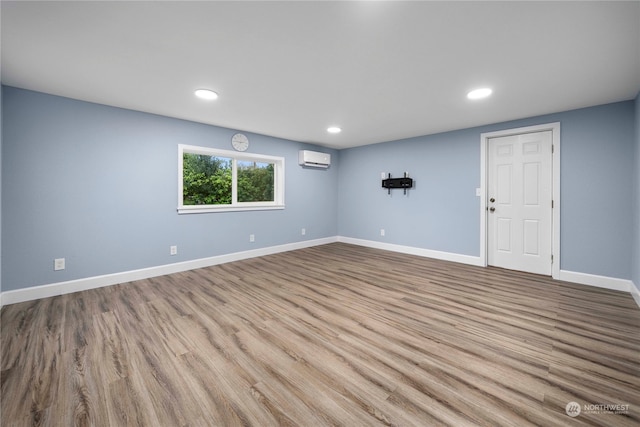 empty room with an AC wall unit and light hardwood / wood-style floors