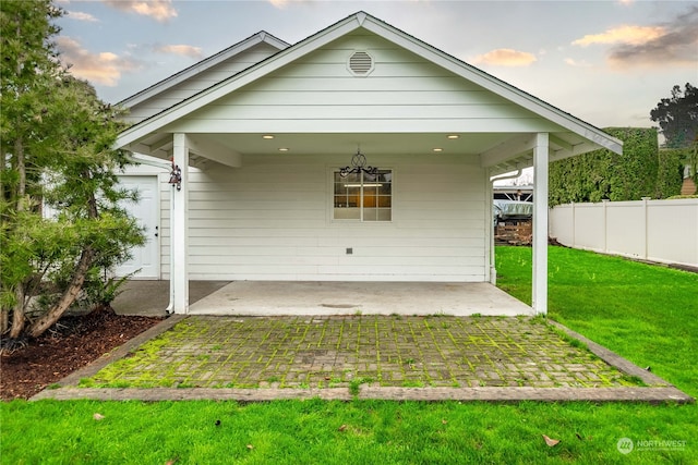 rear view of property with a carport and a yard