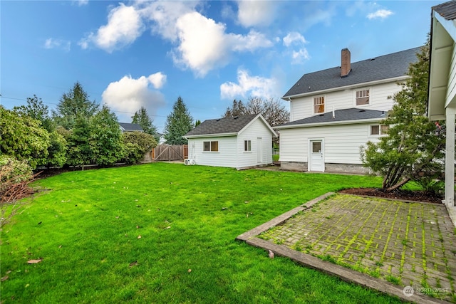 rear view of property featuring a lawn and an outdoor structure