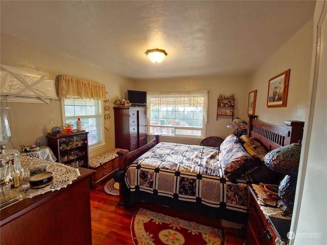 bedroom with a textured ceiling and dark hardwood / wood-style floors